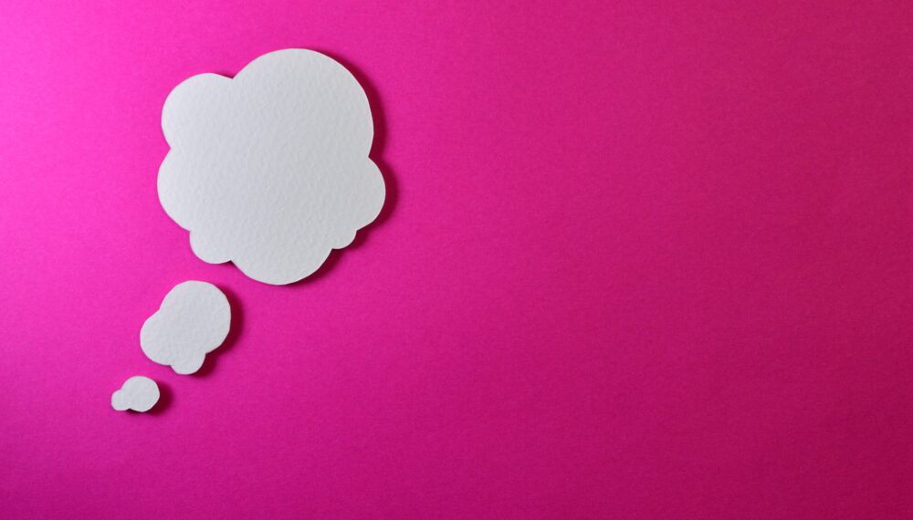 A white thought cloud on a pink background